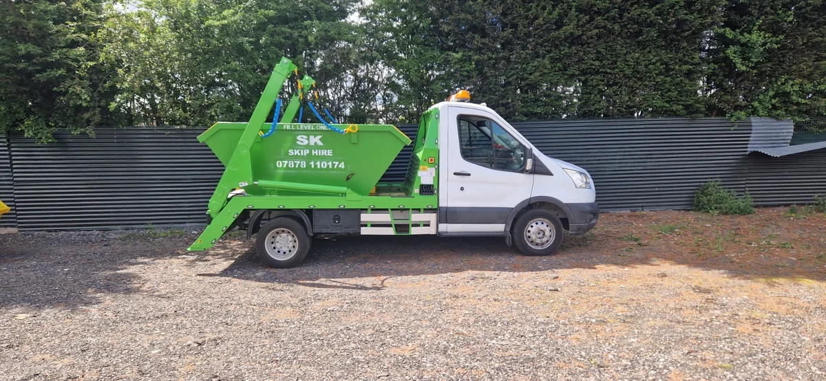 SK’s green skip delivery vehicle in the yard